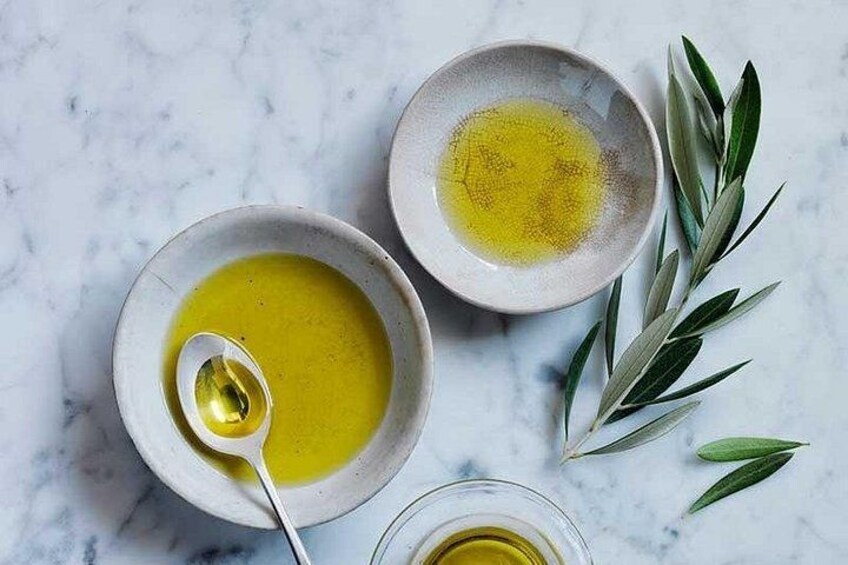 Dos cuencos de aceite de oliva sobre una superficie de mármol, una cuchara y un vaso de aceite de oliva. 5
