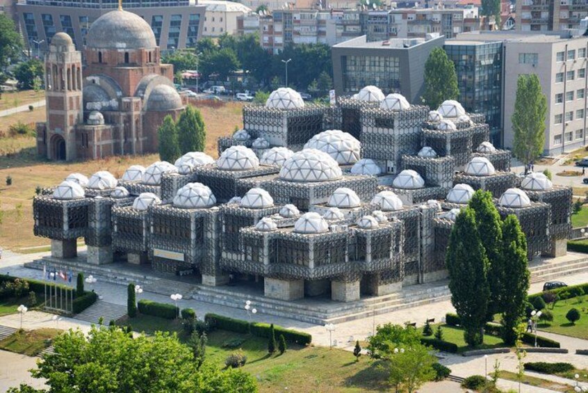 A modern architectural complex with multiple dome structures, surrounded by greenery and urban buildings. 1