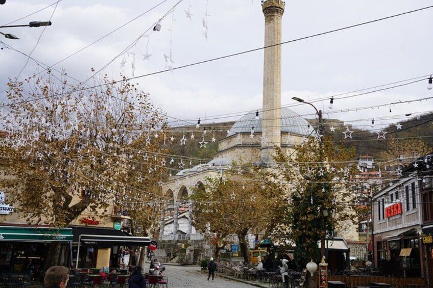 A street scene with a prominent tower, trees, and a building with arches. 4
