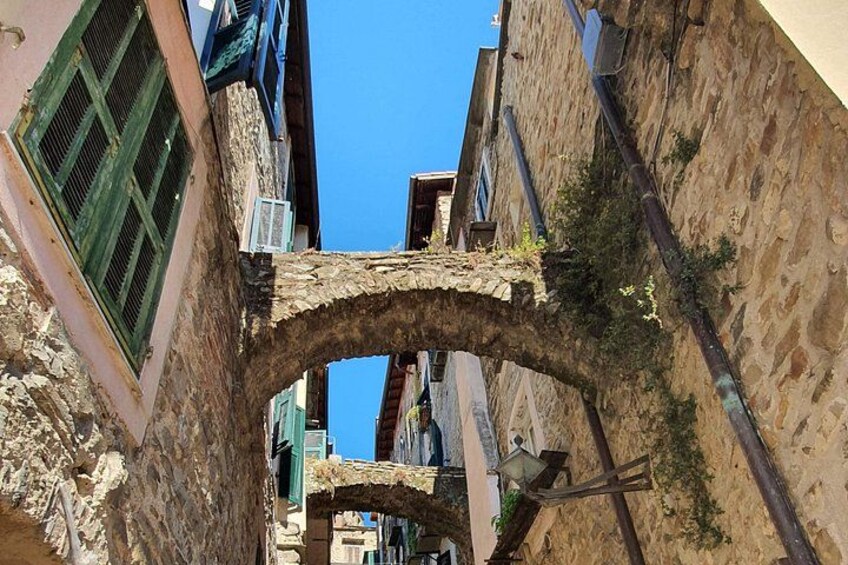 A stone archway in a narrow street with buildings on either side. 3
