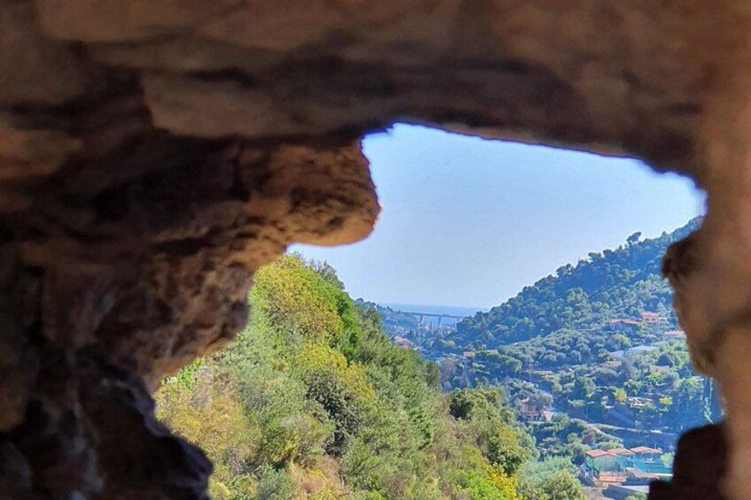 A cave opening with a view of a hilly landscape and a bridge in the distance. 5