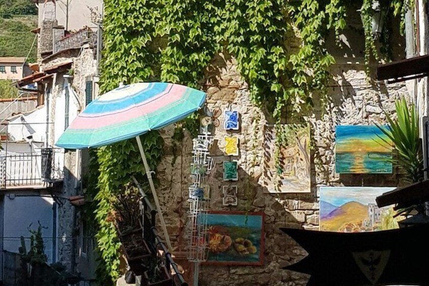 A stone wall with colorful paintings and a striped umbrella. 5