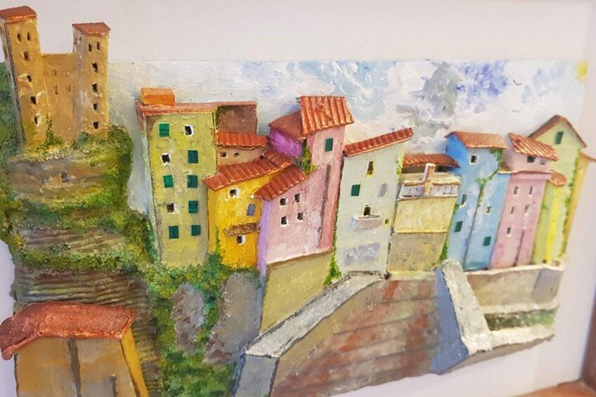 A colorful painting of a village with buildings, a bridge, and a hill. 2