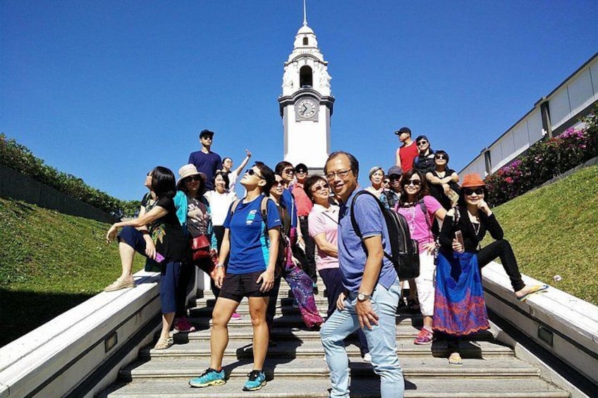 A group of people standing on a staircase with a clock tower in the background. 5