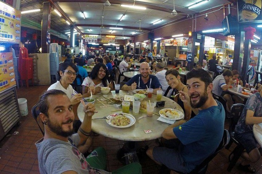 A crowded indoor dining area with people seated at round tables, eating and drinking. 3