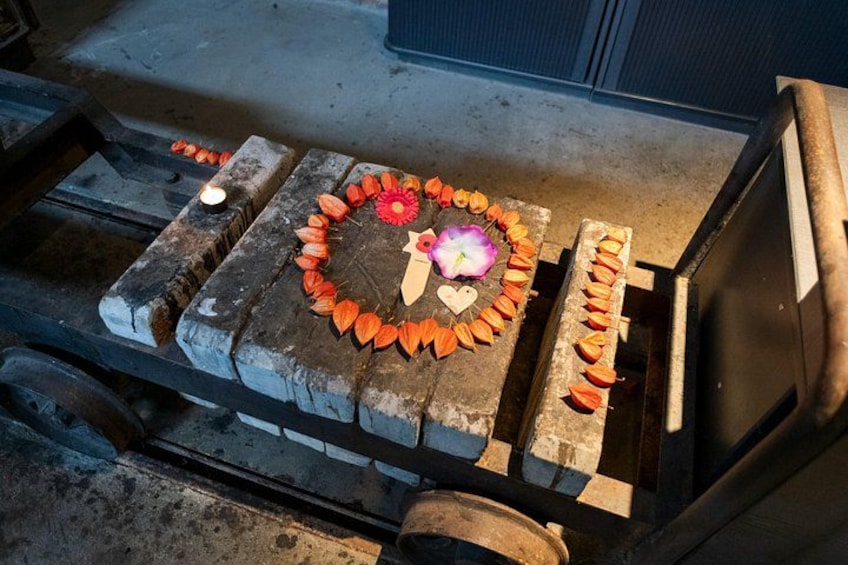 A wooden surface with a circular arrangement of orange leaves and a pink flower, possibly a decorative setup. 2