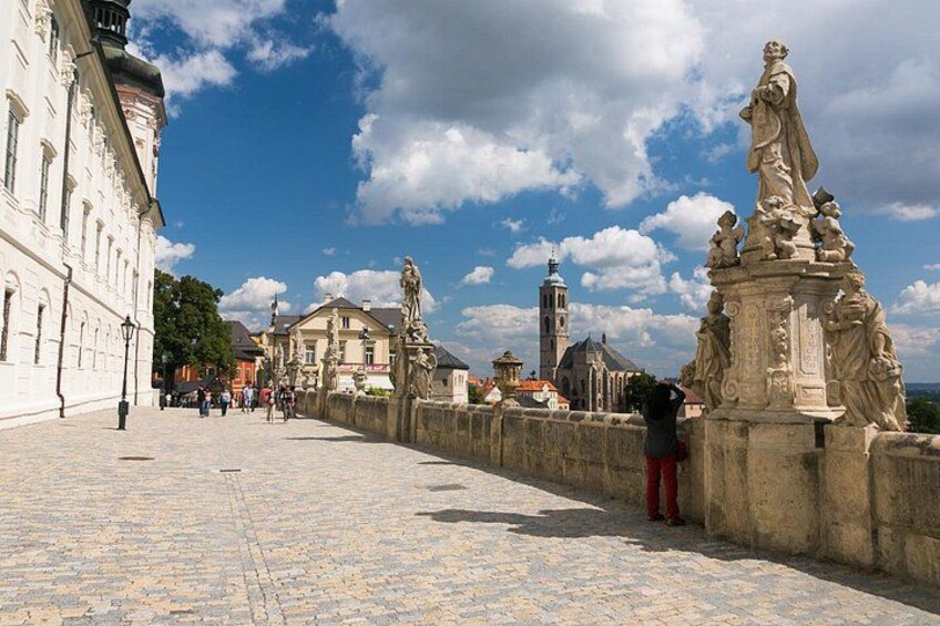 Un puente empedrado con estatuas, un edificio blanco e iglesia con un campanario. 4