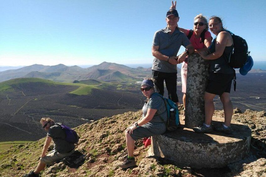 Eine Gruppe von Menschen auf einem Berggipfel mit weitreichendem Panoramablick auf die Landschaft. 1