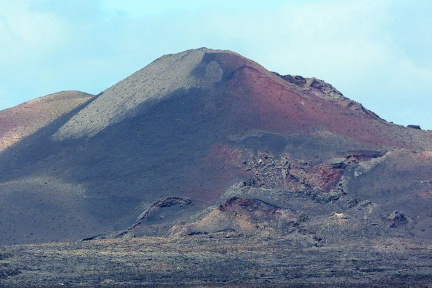A mountain with a reddish peak and a rocky foreground. 4