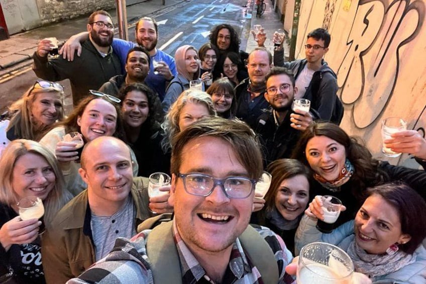 A group of people posing for a photo in an urban setting with graffiti on the wall. 2
