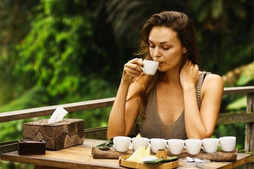 A person sitting at a wooden table outdoors with cups and a box of tissues. 5