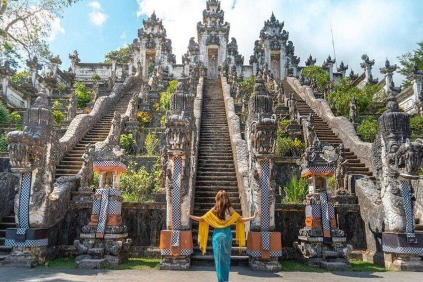 A person standing in front of a grand staircase with ornate balustrades and statues. 2