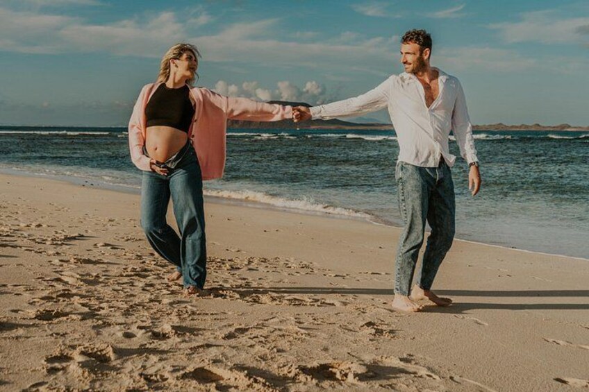 A couple walking hand in hand on a sandy beach with the ocean in the background. 5