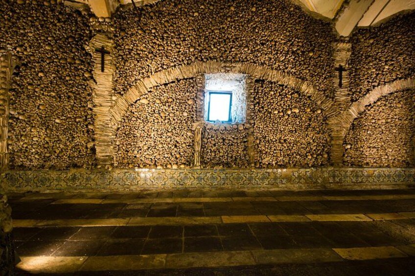 A stone-walled interior with a small window, arched ceilings, and a cross. 3