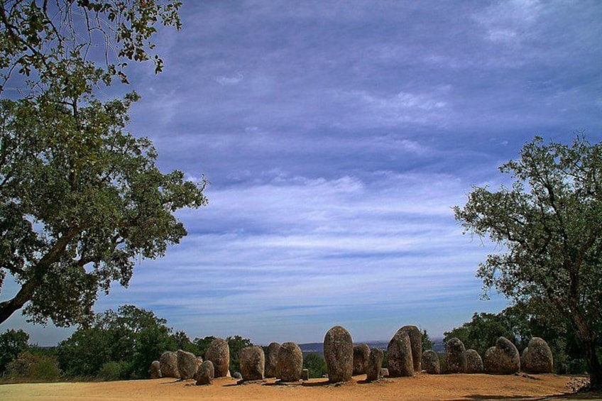 A landscape with a row of standing stones under a cloudy sky. 1