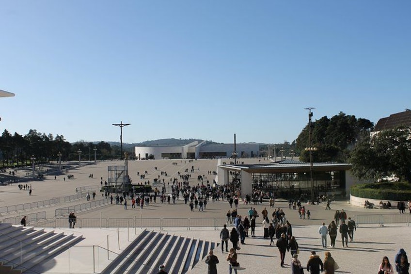 Une vaste place ouverte où l’on voit des gens se promener, un bâtiment moderne et un ciel dégagé. 2