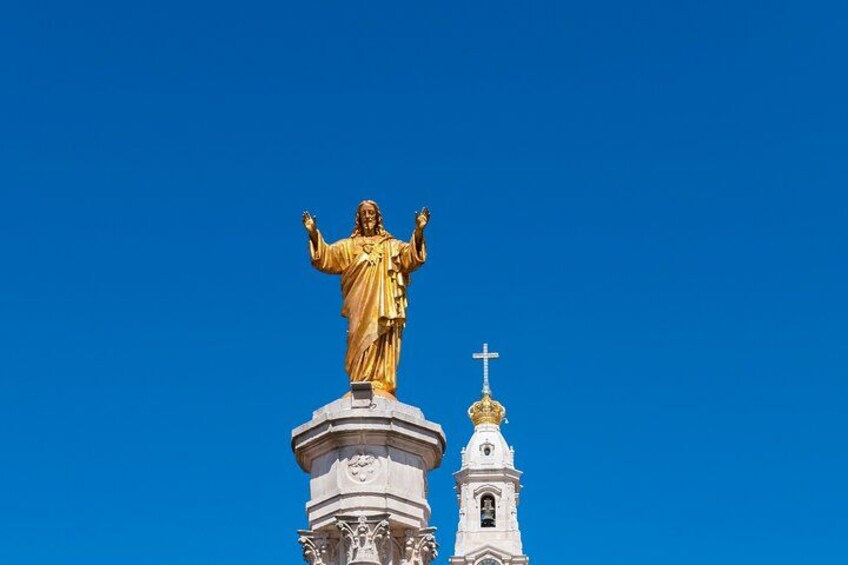 Une statue dorée, placée sur un piédestal, avec un clocher d’église en arrière-plan. 4