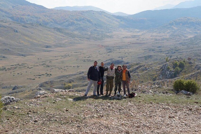 Eine Gruppe von Menschen steht auf einem felsigen Hügel, im Hintergrund eine gebirgige Landschaft. 4