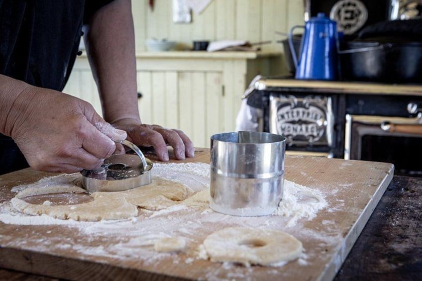 A person using a cookie cutter on dough on a wooden board. 3