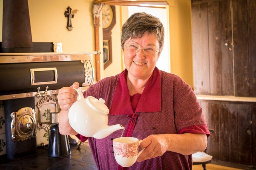 A person pouring tea from a teapot into a cup. 4