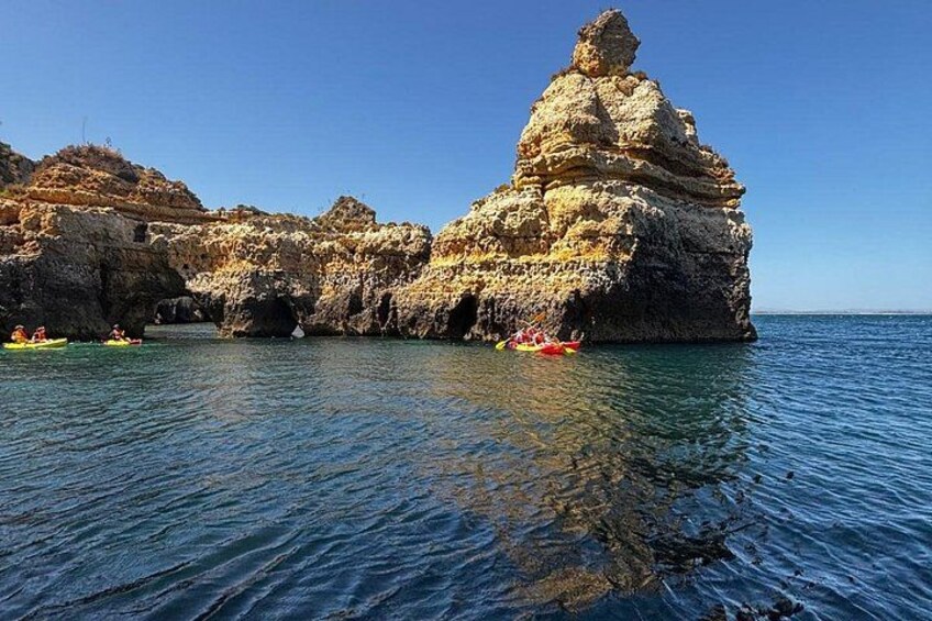 Costa rocosa con una formación rocosa destacada y kayaks en el agua. 5