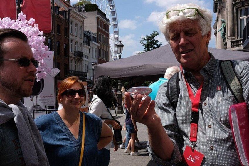 Eine Person mit roter Ausweishalterung und Namensschild steht draußen vor einer Gebäudebäckgrund. 5