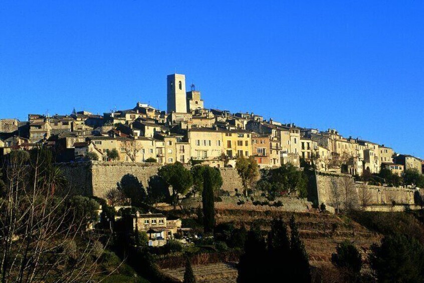 A historic town with a prominent tower, terraced fields, and dense architecture. 5