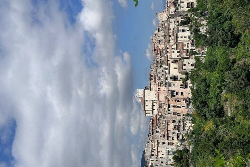 A coastal town with buildings nestled among lush greenery. 3
