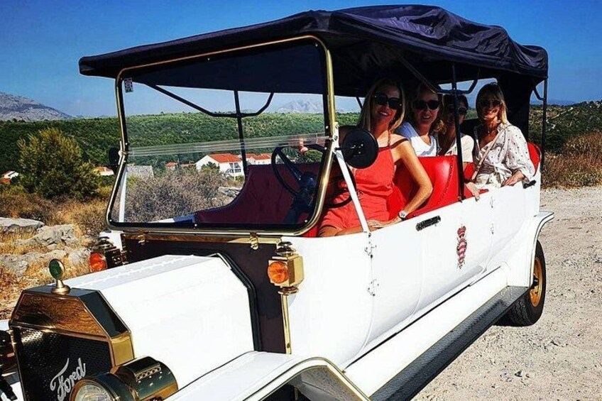 A vintage car with a black roof and passengers. 2