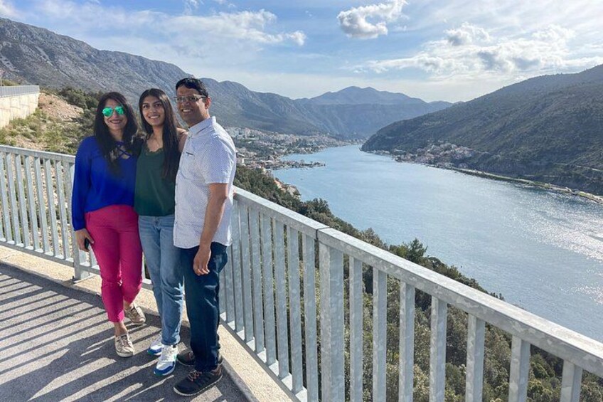A group of people on a wooden walkway overlooking a lake with mountains in the background. 3