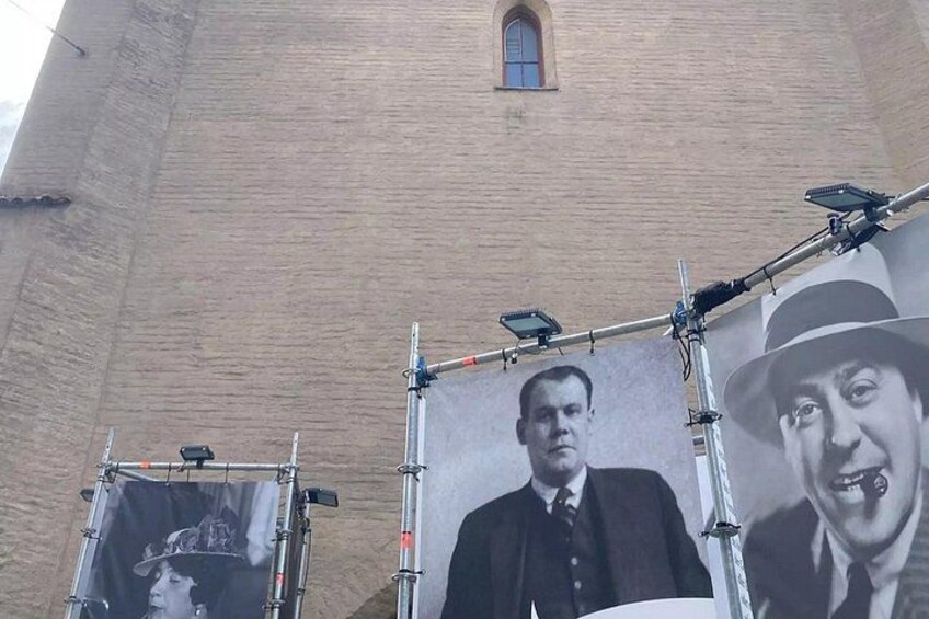 A large brick building with a small window and a banner with portraits. 2