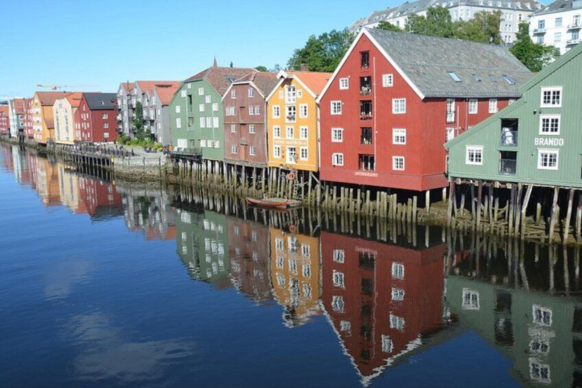 Una hilera de casas de madera coloridas junto a un cuerpo de agua tranquilo, que refleja los edificios. 1