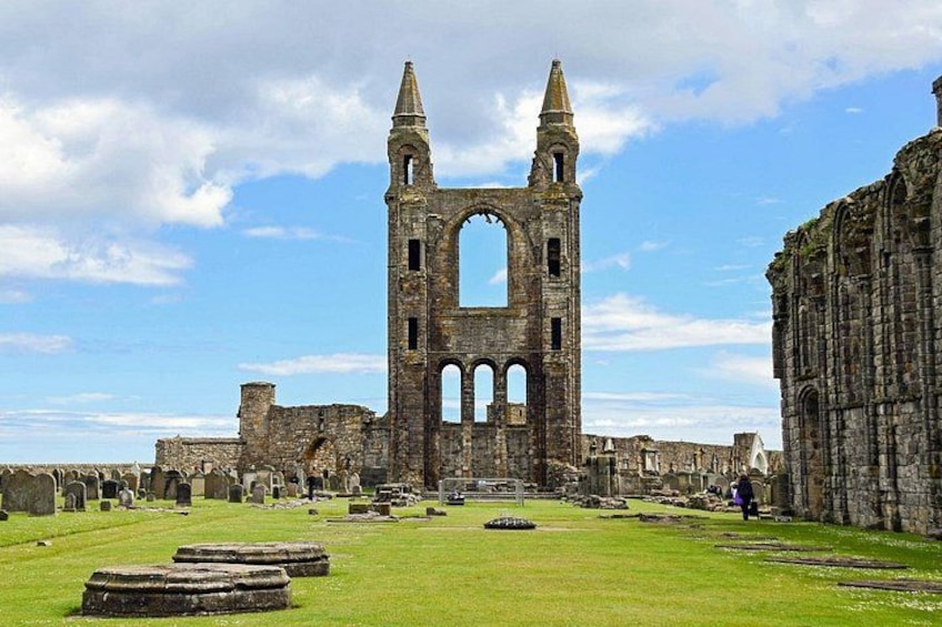 A historic stone structure with arches and a tower, surrounded by a cemetery with headstones. 1