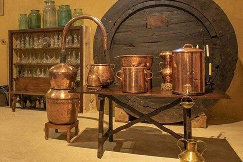 Antique copper cookware on a table with a wooden background and a large barrel. 4