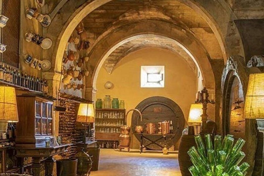 An interior with arched ceilings, shelves with bottles, and a large green glass sculpture. 3