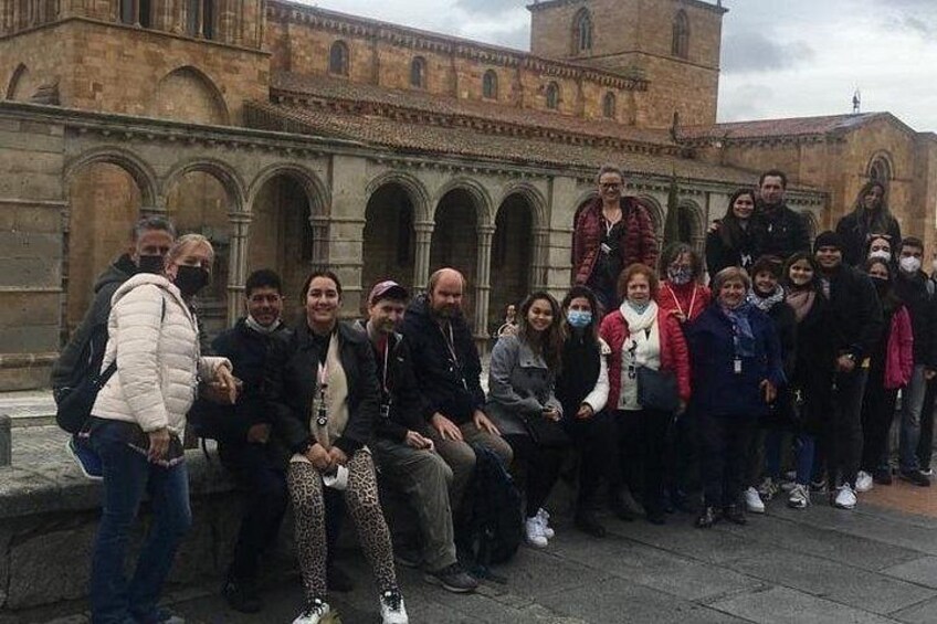 Un gruppo di persone che posa davanti a un edificio storico con archi e una torre. 3