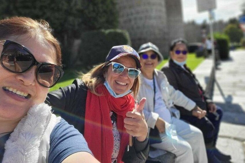 Un gruppo di persone sedute su una panchina all'aperto, con un edificio in pietra sullo sfondo. 4