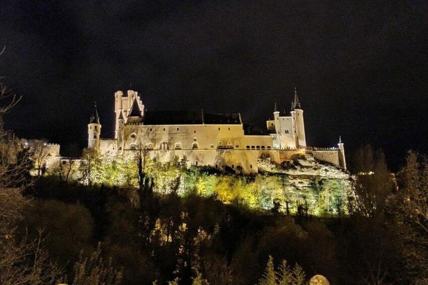 A castle illuminated at night with multiple towers and a moat. 3