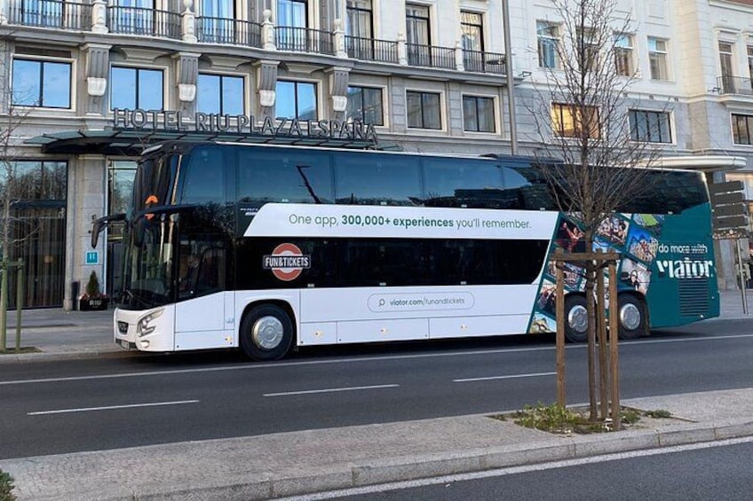 A double-decker bus with advertisements on its side, parked on a city street. 5