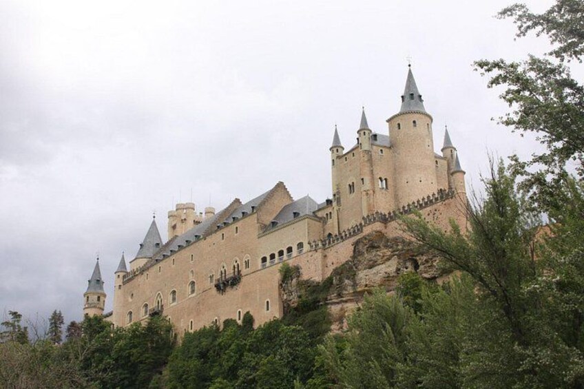 A large castle with multiple towers, situated on a hill surrounded by greenery. 4