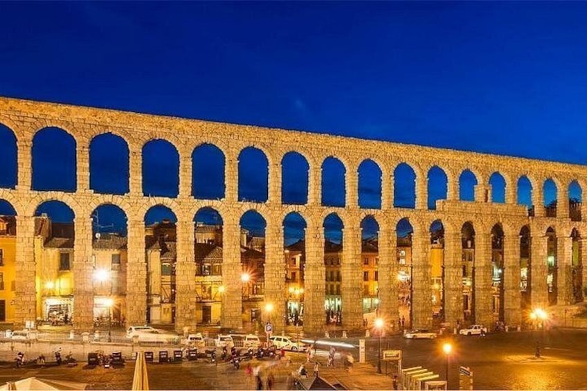 Un acquedotto in pietra illuminato da luci di notte, con archi ben visibili. 2