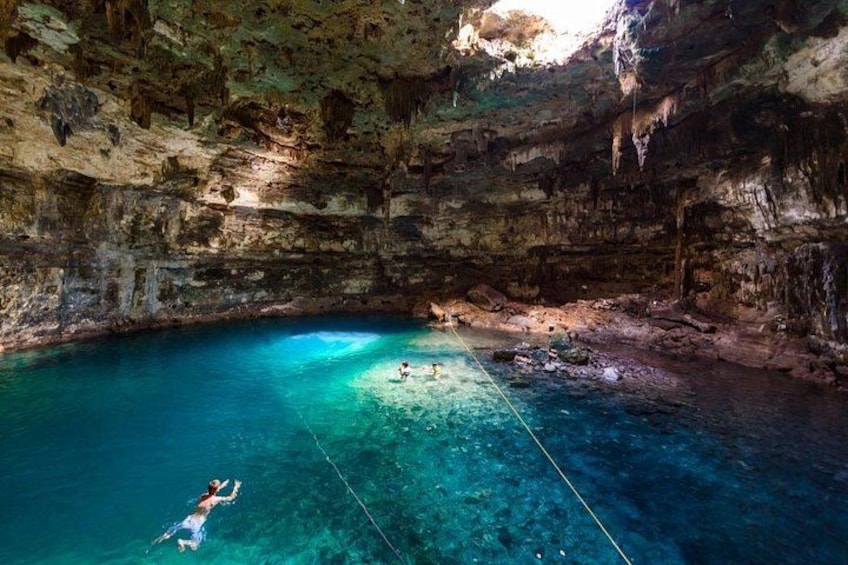 Una persona flota sobre una cuerda en una piscina azul cristalina dentro de una cueva. 2