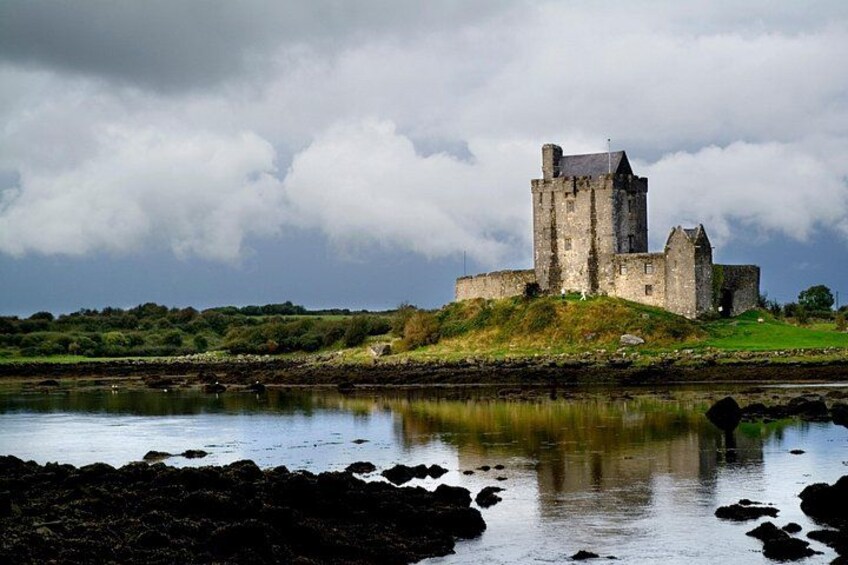 A castle on a hill overlooking a body of water, with a cloudy sky above. 3