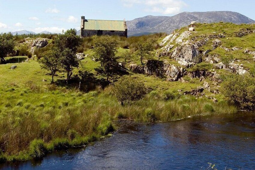 A rural landscape with a stone building, a stream, and a grassy hill. 2