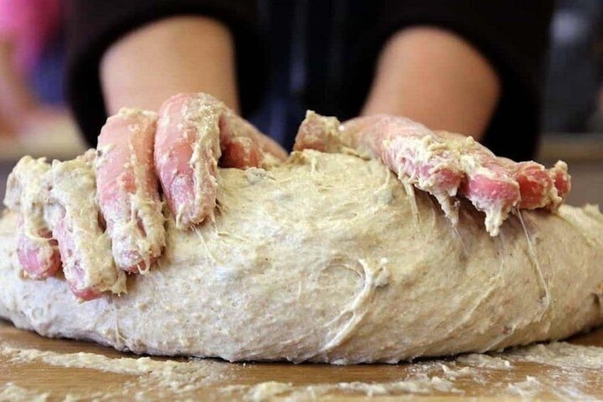 Hands kneading dough on a wooden surface. 3