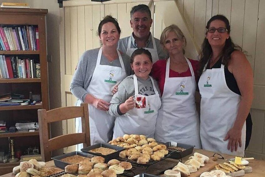 A group of people wearing aprons with a logo, standing in front of a table with baked goods. 4