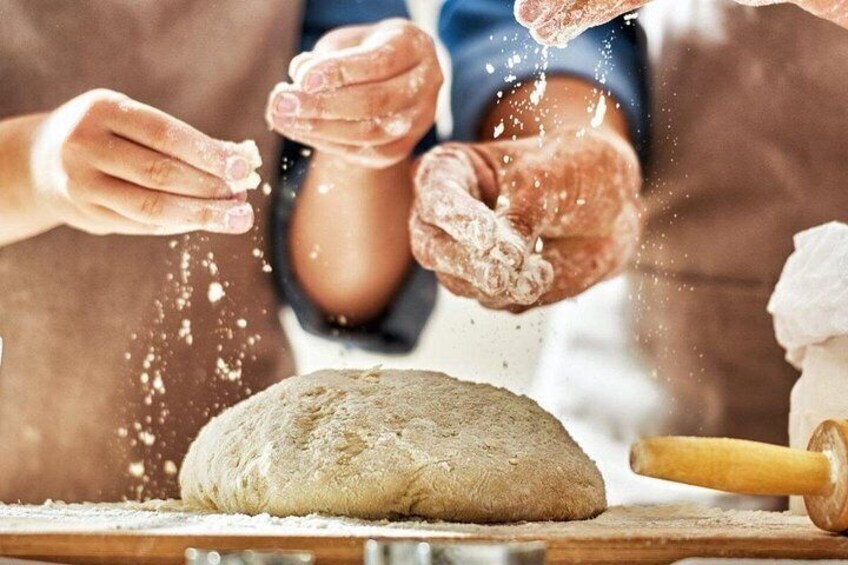 Hands shaping dough on a wooden surface with a rolling pin nearby. 2