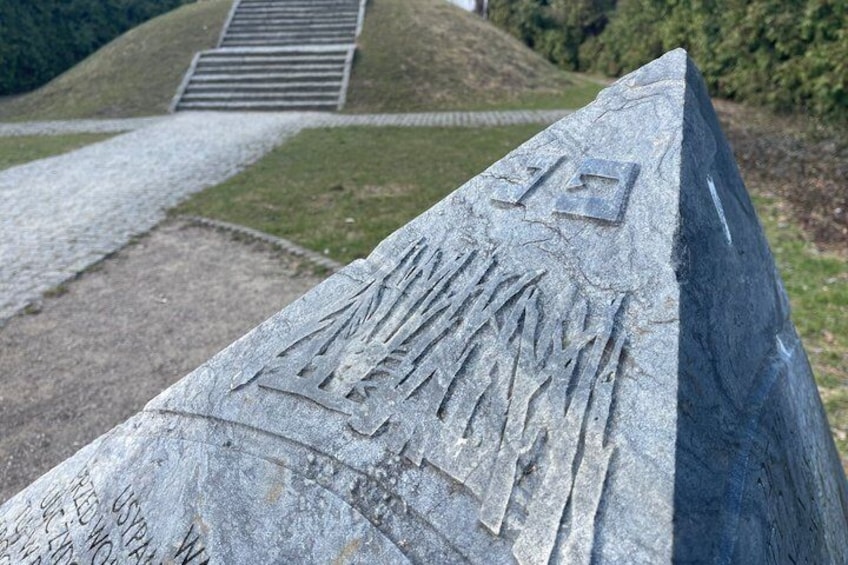 A stone monument with engraved text and a pathway leading to a hill. 4