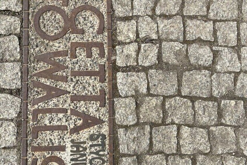 A cobblestone pavement with engraved text reading 'GET A JOB' and 'STOCK JAMAICA.' 5