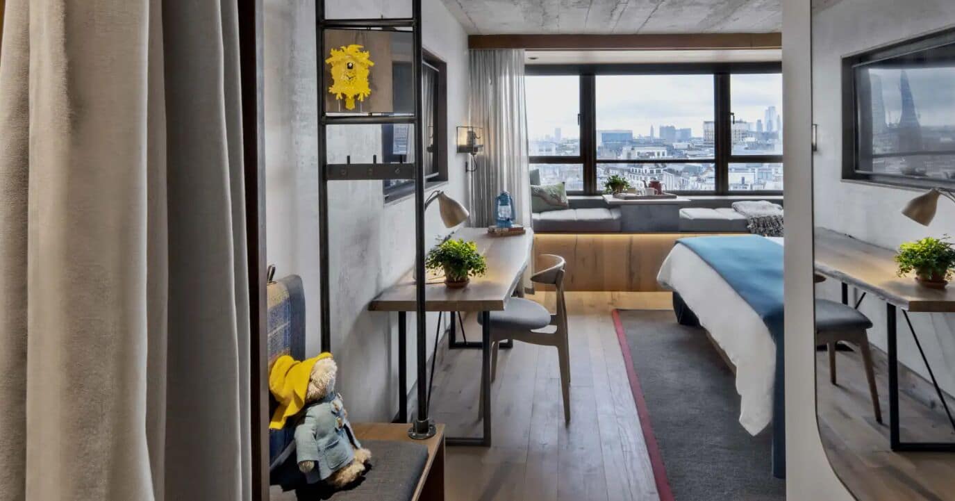 Una habitación de hotel moderna con vista a la ciudad, un sofá, un escritorio y una cama.
